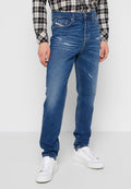 Blaue Denim-Jeans mit geradem Bein, ausgewaschenem Frontbereich und klassischem fünf-taschen Design, kombiniert mit weißen Sneakers und einem schwarz-weißen karierten Hemd.