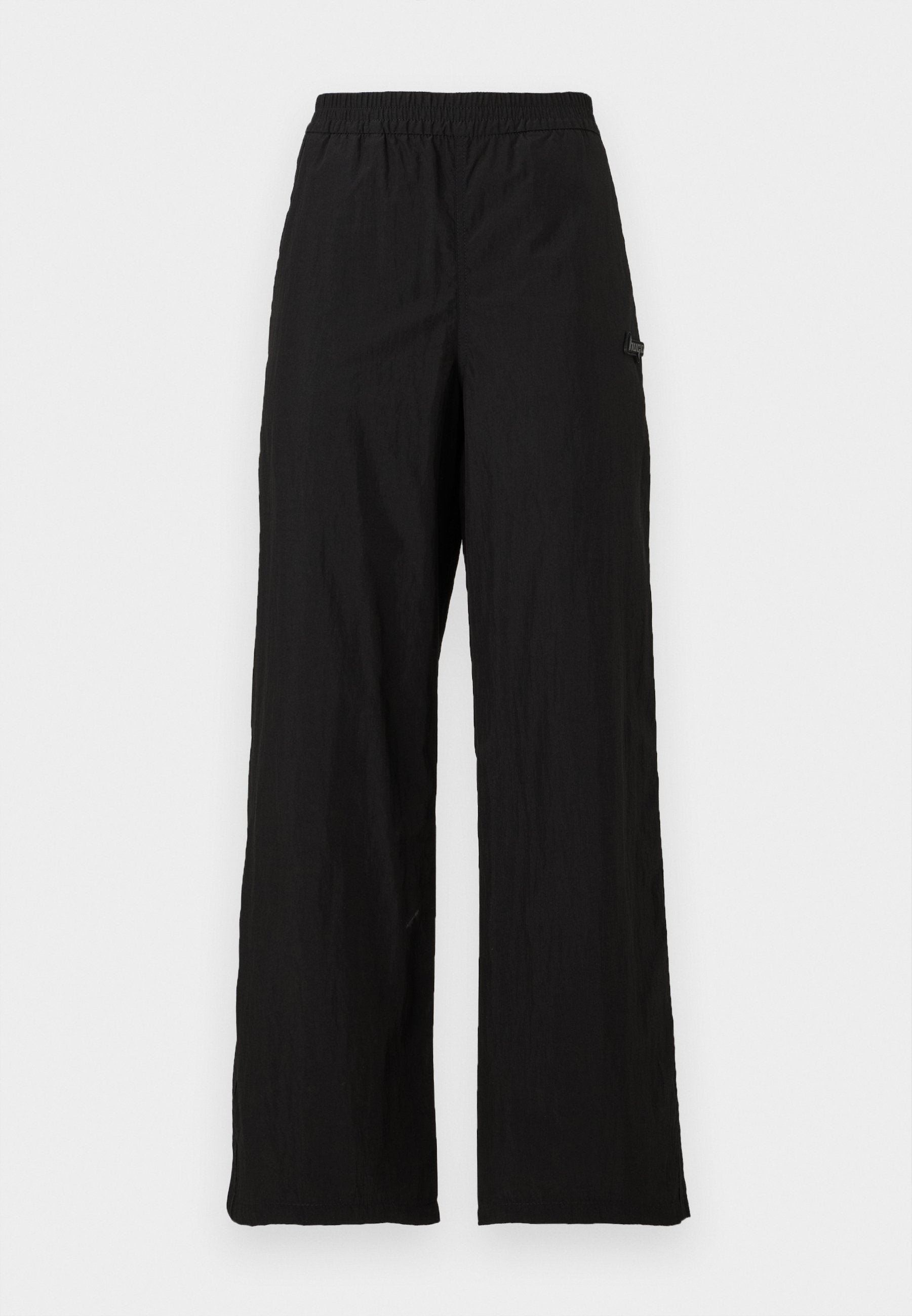 Schwarze weite Hose mit elastischem Bund, aus leichtem Stoff gefertigt, mit einer subtilen Textur und einem seitlichen Logo-Akzent.