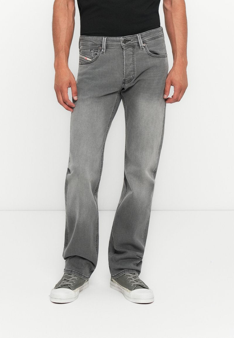 Graue Jeans aus Denim mit geradem Bein, fünf Taschen und subtilen Ausbleichungen. Kombiniert mit grünen Turnschuhen für einen lässigen Look.