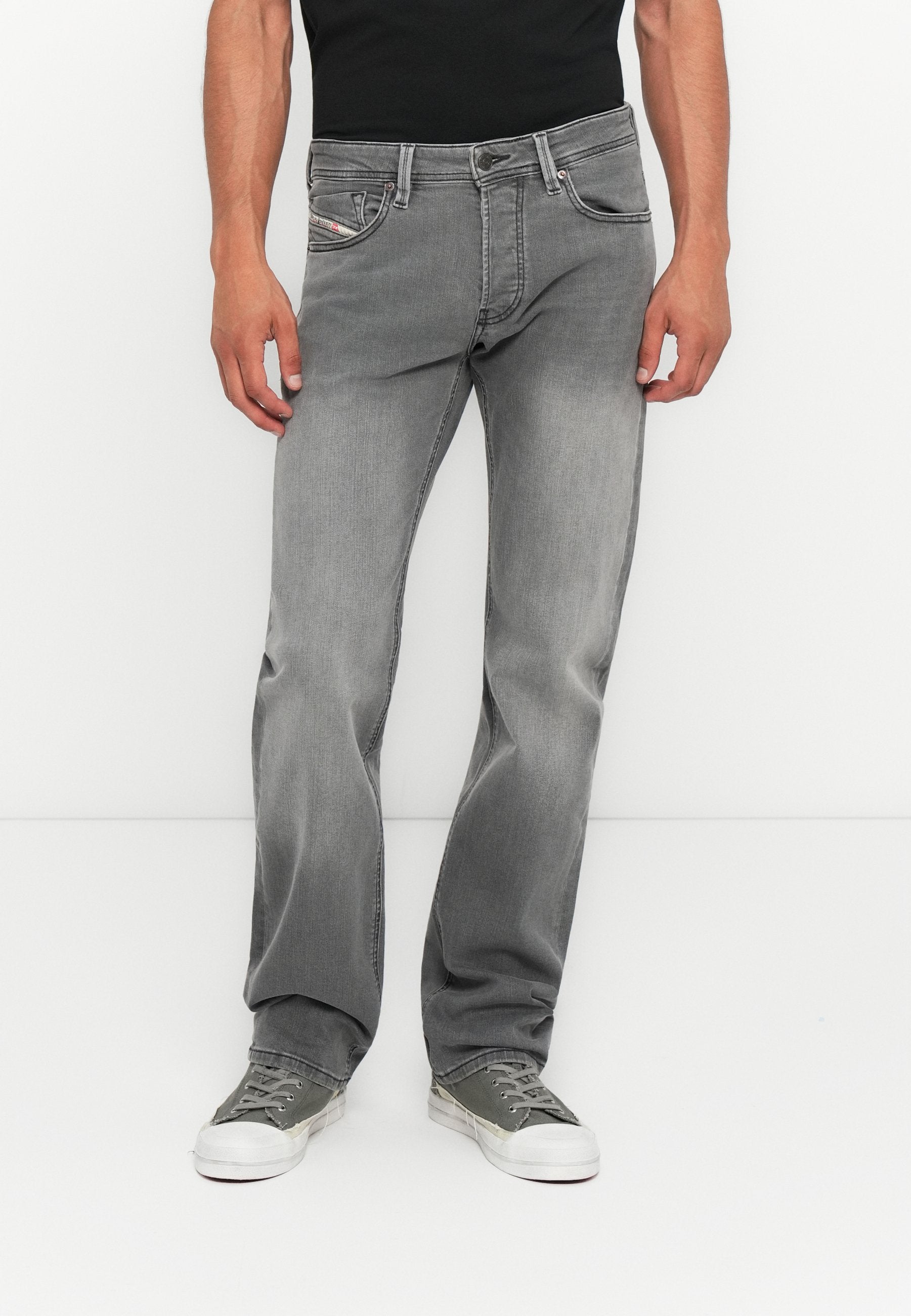 Graue Jeans aus Denim mit geradem Bein, fünf Taschen und subtilen Ausbleichungen. Kombiniert mit grünen Turnschuhen für einen lässigen Look.