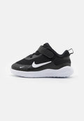 Schwarze Mesh-Sneaker mit einem weißen Nike-Logo, verstellbarem Riemen und einer strukturierten weißen Sohle. Runde Form mit verstärktem Fersenbereich.