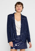 Navy-Blazer mit Pailletten, einem Reverskragen, zwei Fronttaschen und langen Ärmeln, getragen über einer hellen Satinbluse und einem glänzenden Minirock.