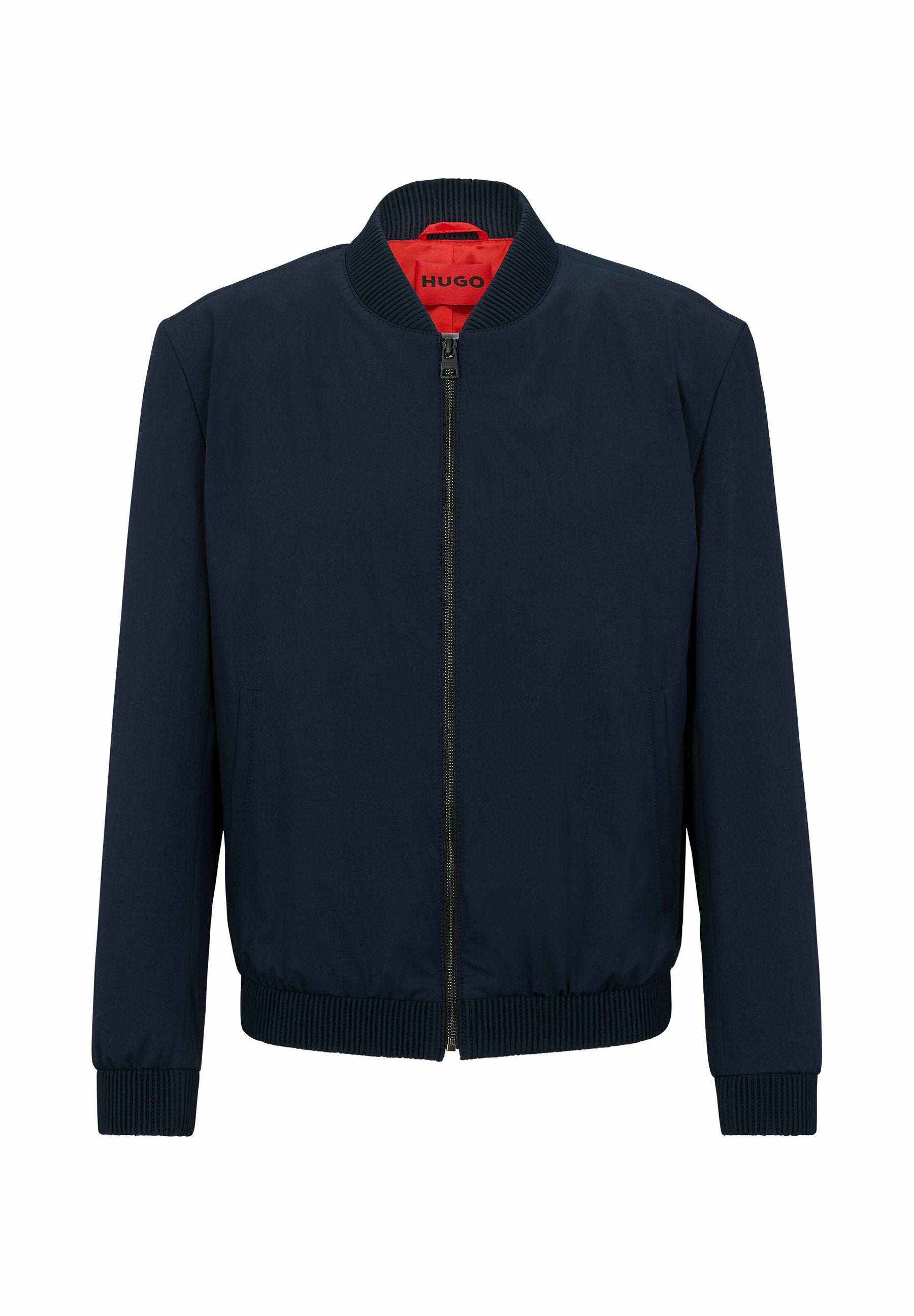 Marineblaue Bomberjacke mit Reißverschluss, geripptem Kragen, Bündchen und Saum, ausgestattet mit einem roten Innenfutter und seitlichen Taschen. Glatte Textur.