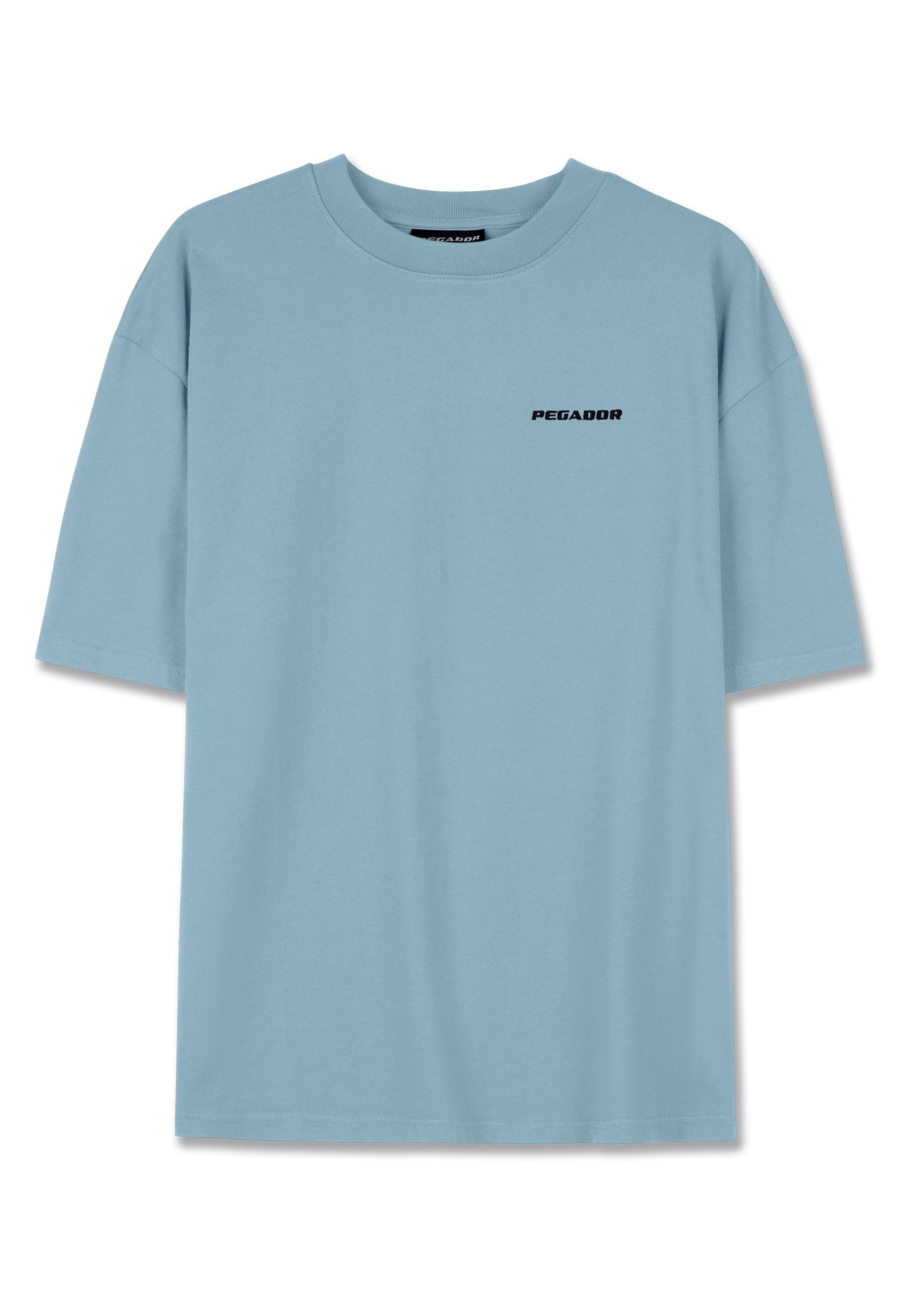 Hellblaues Baumwoll-T-Shirt mit lockerer Passform, kurzen Ärmeln und schwarzem "PEGADOR"-Logo auf der Brust. Weicher Stoff, keine zusätzlichen Muster.