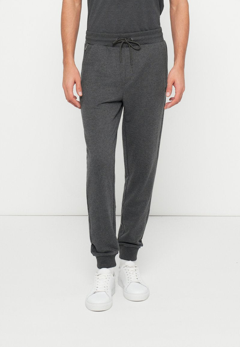 Graue Jogginghosen aus weichem Stoff mit elastischem Bund und Kordelzug, Seitentaschen und gerippten Bündchen.
