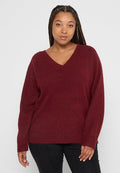 Burgunderfarbener Strickpullover mit V-Ausschnitt, langen Ärmeln und seitlichen Schlitzen, hergestellt aus einem weichen, strukturierten Stoff für Komfort.