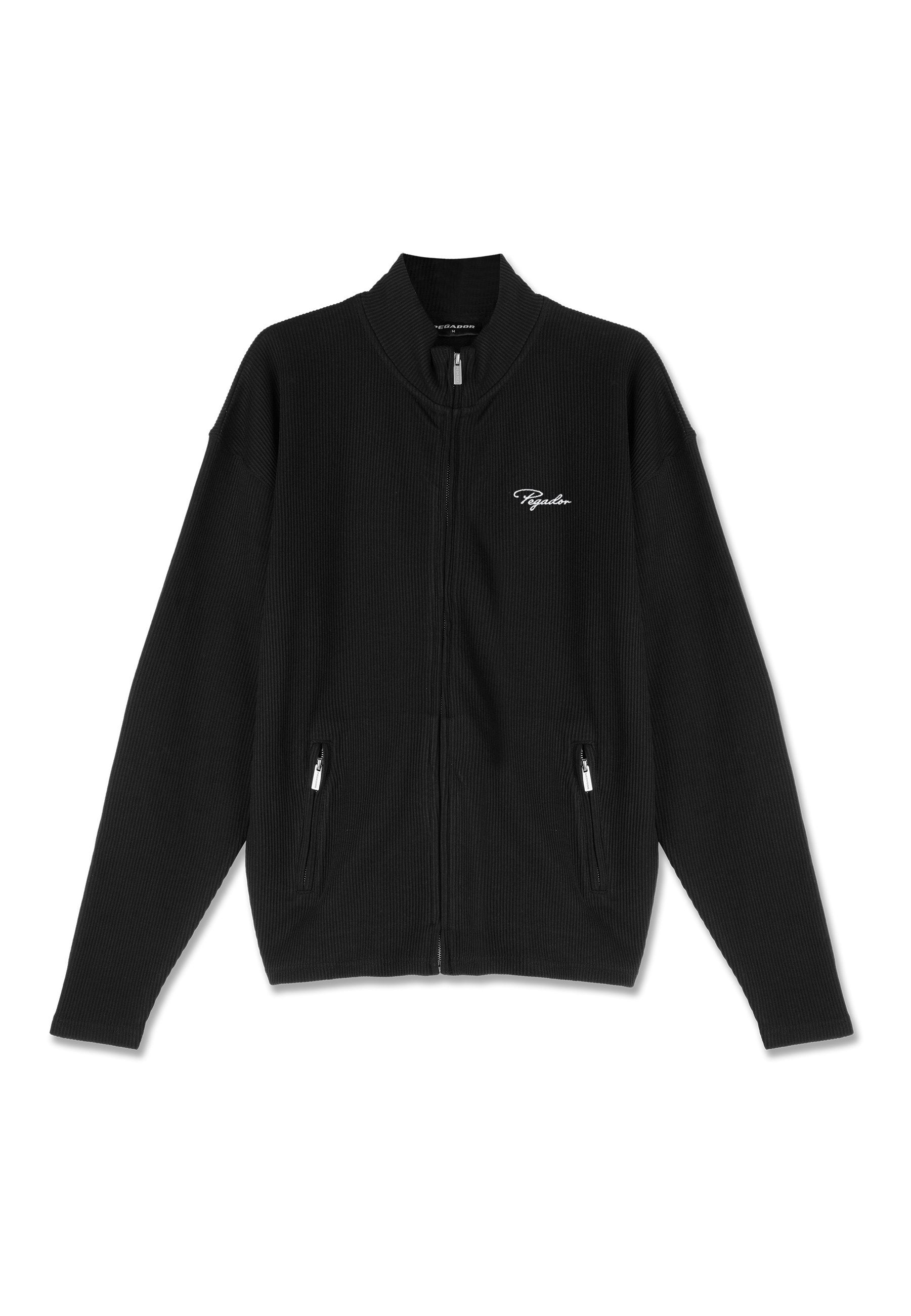 Schwarze Jacke mit Reißverschluss, gerippter Textur, langen Ärmeln, zwei Reißverschlusstaschen und kleinem weißen kursivem Logo auf der linken Brust.