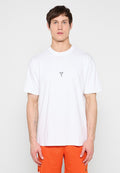 Junger Mann in weißem "Mamba Forever" T-Shirt und orangefarbenen Shorts steht vor hell einfarbigem Hintergrund.