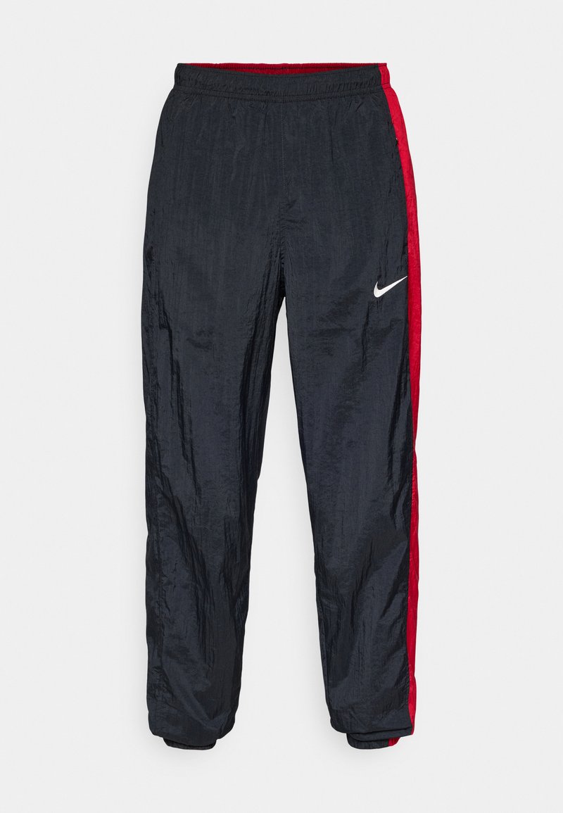 Nike Trainingshosen in Schwarz mit roten Seitenstreifen, elastischem Bund und schmal zulaufenden Bündchen. Hergestellt aus glattem, leichtem Material.