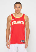 Junger Mann trägt ein rotes Atlanta-Basketballtrikot und weiße Shorts, steht vor einem schlichten weißen Hintergrund und schaut nach vorne.