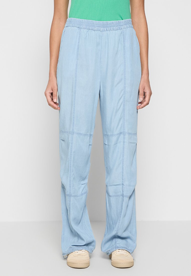 Hellblaue, locker sitzende Hosen mit einem Kordelzugbund, die mit Nähdetails und Seitentaschen versehen sind, aus weichem, atmungsaktivem Stoff gefertigt.
