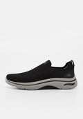 Schwarzer Slip-On Sneaker mit gestricktem Obermaterial, grauer gepolsterter Sohle und "Arch Fit"-Label an der Seite.