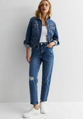 Jeansjacke mit Kragen, vorderen Taschen und Knopfverschluss. Weißes Tanktop kombiniert mit hoch geschnittenen, verwaschenen blauen Jeans und weißen Turnschuhen.
