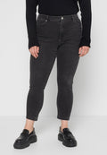 Schwarze Jeans aus Denim mit schmalem Schnitt, ausgestattet mit Vordertaschen, einem Knopfverschluss und einer mittelhohen Taille, kombiniert mit Plateauslippern.