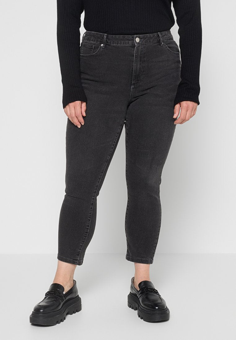 Schwarze Jeans aus Denim mit schmalem Schnitt, ausgestattet mit Vordertaschen, einem Knopfverschluss und einer mittelhohen Taille, kombiniert mit Plateauslippern.