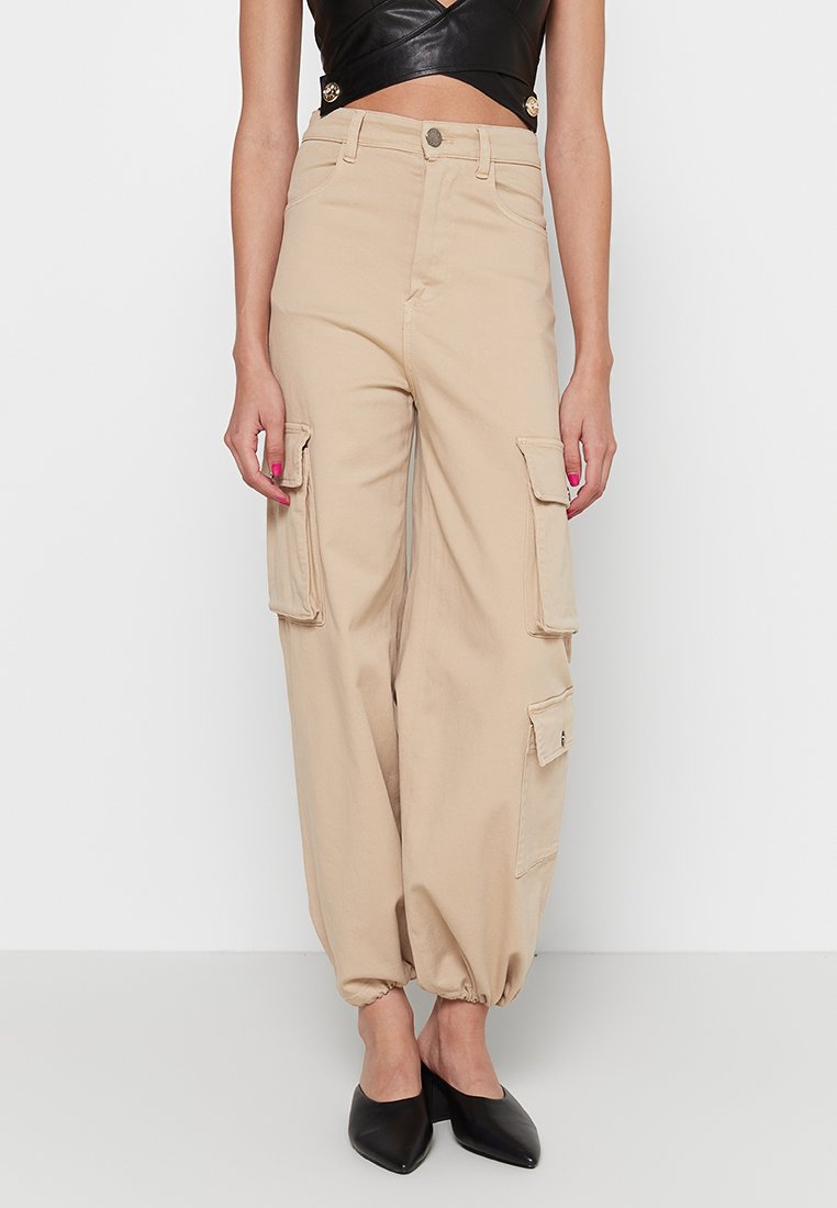 Beige Cargo-Hosen mit lockerer Passform, seitlichen Taschen, elastischen Bündchen und hoher Taille. Aus einem robusten Stoff mit glatter Textur gefertigt.