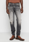 Schwarze und graue Jeans aus Denim mit einem verblassten Effekt, distressed Details und einem geraden Bein, kombiniert mit braunen Stiefeletten.