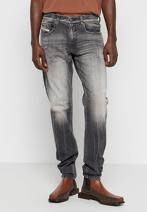 Schwarze und graue Jeans aus Denim mit einem verblassten Effekt, distressed Details und einem geraden Bein, kombiniert mit braunen Stiefeletten.