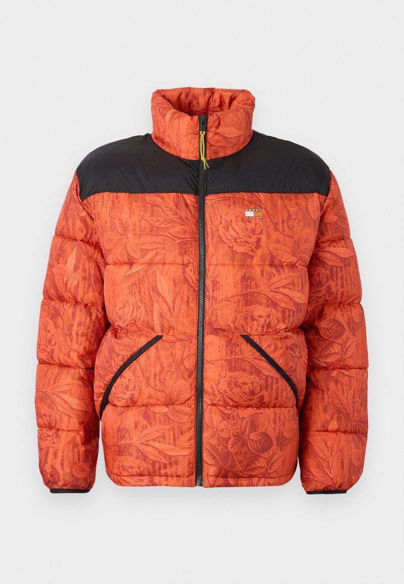 Puffjacke mit einem orangefarbenen Blumenmuster, schwarzen Schultern, Reißverschluss vorne und zwei seitlichen Taschen mit kontrastierendem schwarzen Besatz.