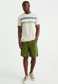 Beige T-Shirt für Herren mit grünen, blauen und weißen Streifen, kombiniert mit grünen Shorts. Aus Baumwollmaterial, einfaches Design, lässiger Schnitt. Beige Sneaker.