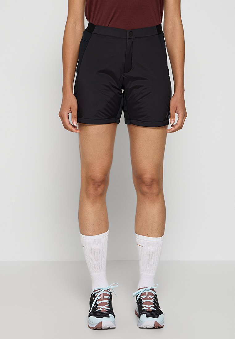 Schwarze sportliche Shorts mit glatter Textur, Knopfverschluss und elastischem Bund, kombiniert mit weißen Kniesocken und gemusterten Sneakers.