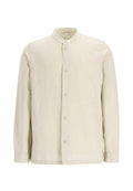 Helle beige Knopf-bluse aus weichem Stoff, mit Stehkragen, vorderen Knöpfen und einem kleinen Logo-Patch auf der linken Brust.