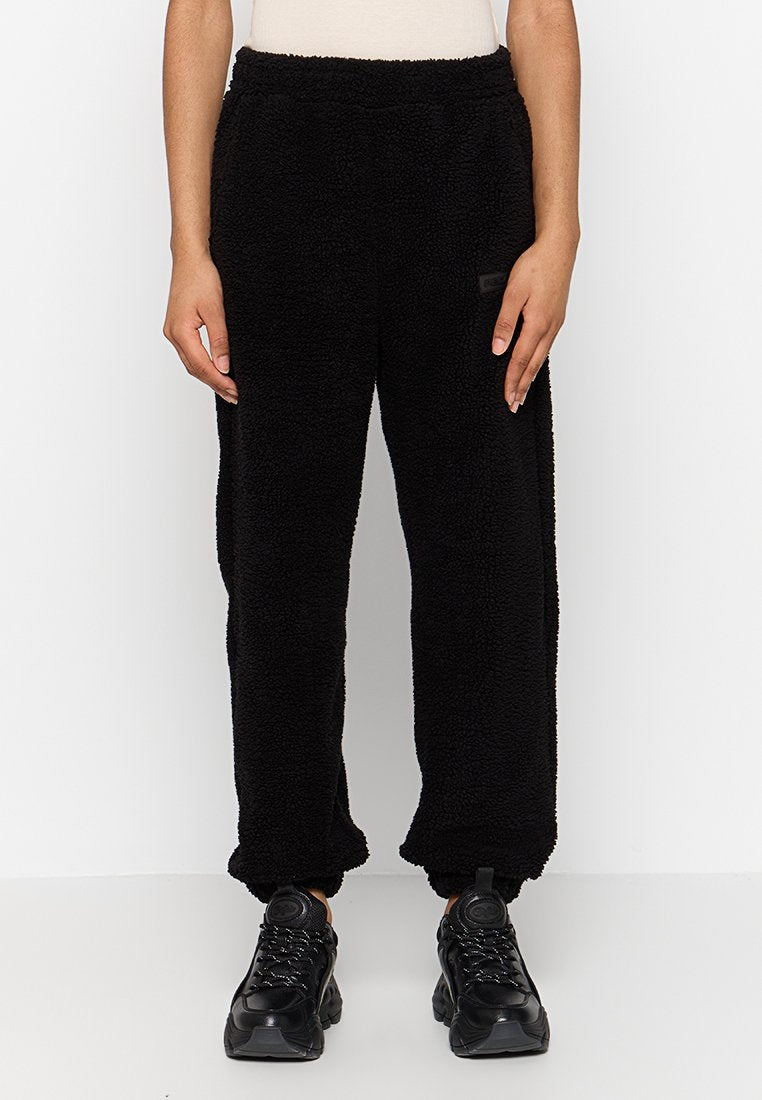 Schwarze, flauschige Jogginghosen mit elastischem Bund, abschließendem Saum und leichtem Glanz. Mit einem kleinen Logopatch an der Seite.