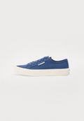 Blaue Leinenschuhe mit niedriger Schnittform und einer weißen Gummisohle, runder Zehenpartie und kontrastierenden Schnürsenkeln. Besitzt ein kleines Logo-Tag an der Seite.