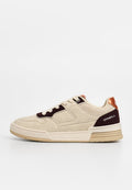 Beige Sneaker mit einer Wildleder-Oberfläche, dunkelbraunen Akzenten und einer metallischen orangefarbenen Ferse. Mit Schnürverschluss und strukturierten Gummisohle.