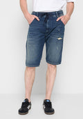 Mann trägt blaue, ausgewaschene Denimshorts mit Kordelzug und schwarze Adidas Sneaker, steht mit den Händen in den Taschen.