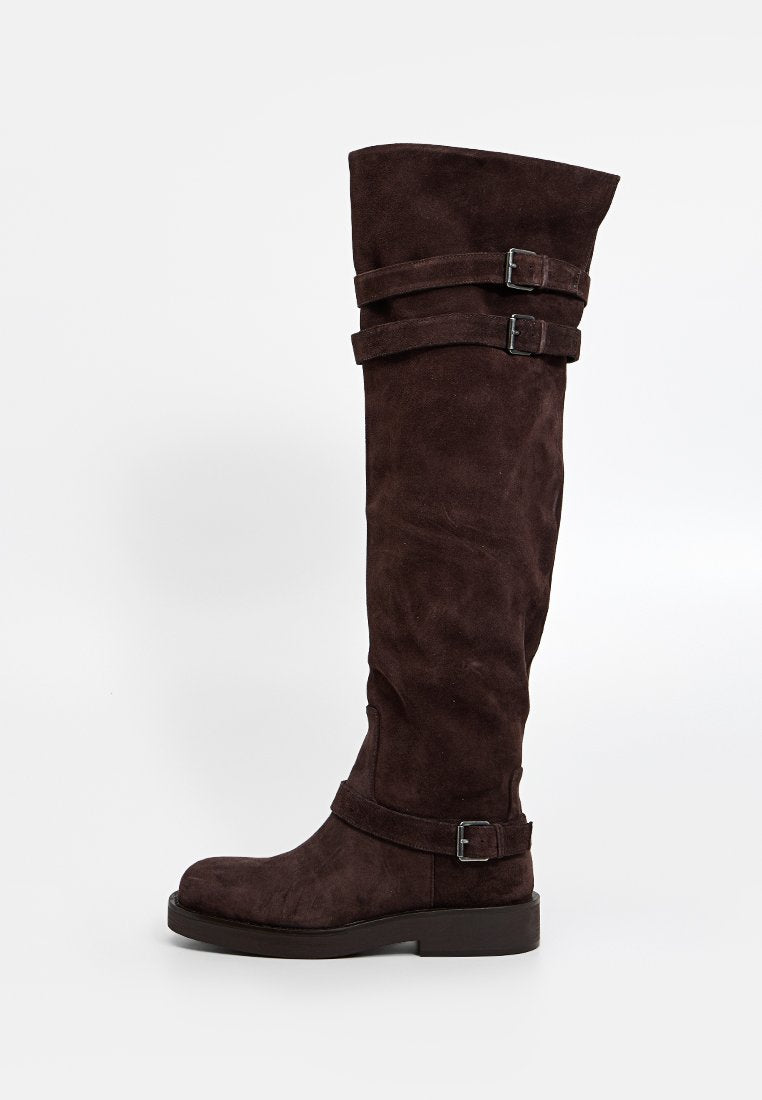 Kniehohe braune Wildlederstiefel mit doppelten Riemen und metallischen Schnallen, ausgestattet mit einer abgerundeten Spitze und flacher Sohle für Komfort.