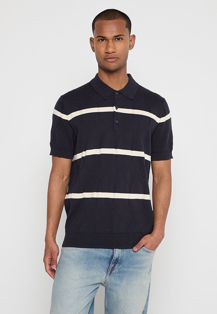 Marineblaues Poloshirt mit kurzen Ärmeln und cremefarbenen Streifen, versehen mit einem strukturierten Rautenmuster und einem Kragen; mit vorderem Knopfverschluss.
