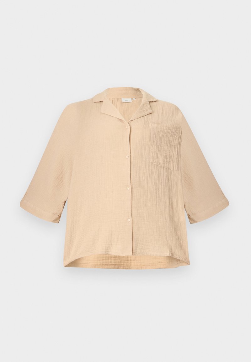 Beige, locker sitzendes, strukturiertes Hemd mit Knöpfen, halblangen Ärmeln, kleinem Kragen und einer einzelnen Brusttasche, auf einem schlichten Hintergrund gezeigt.
