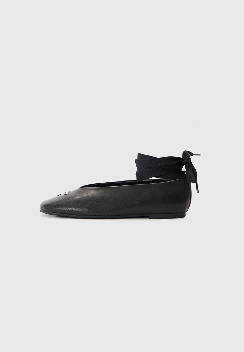 Schwarze Leder-Ballerinas mit spitzem Zehenbereich, ausgestattet mit einem gewebten Stoff-Ankle-Tie und einem kleinen dekorativen Akzent auf der Zehe.