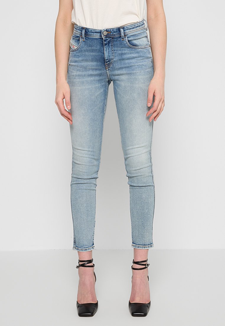 Hellblaue Jeans aus Denim mit slim fit, fünf Taschen, Gürtelschlaufen und ausgefranstem Saum. Getragen mit schwarzen spitzen Absätzen.