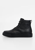 Schwarze High-Top-Schuhe aus Leder mit strukturierter Oberfläche, flacher schwarzer Sohle und Metallösen. Auf der Außenseite befindet sich ein Etikett.