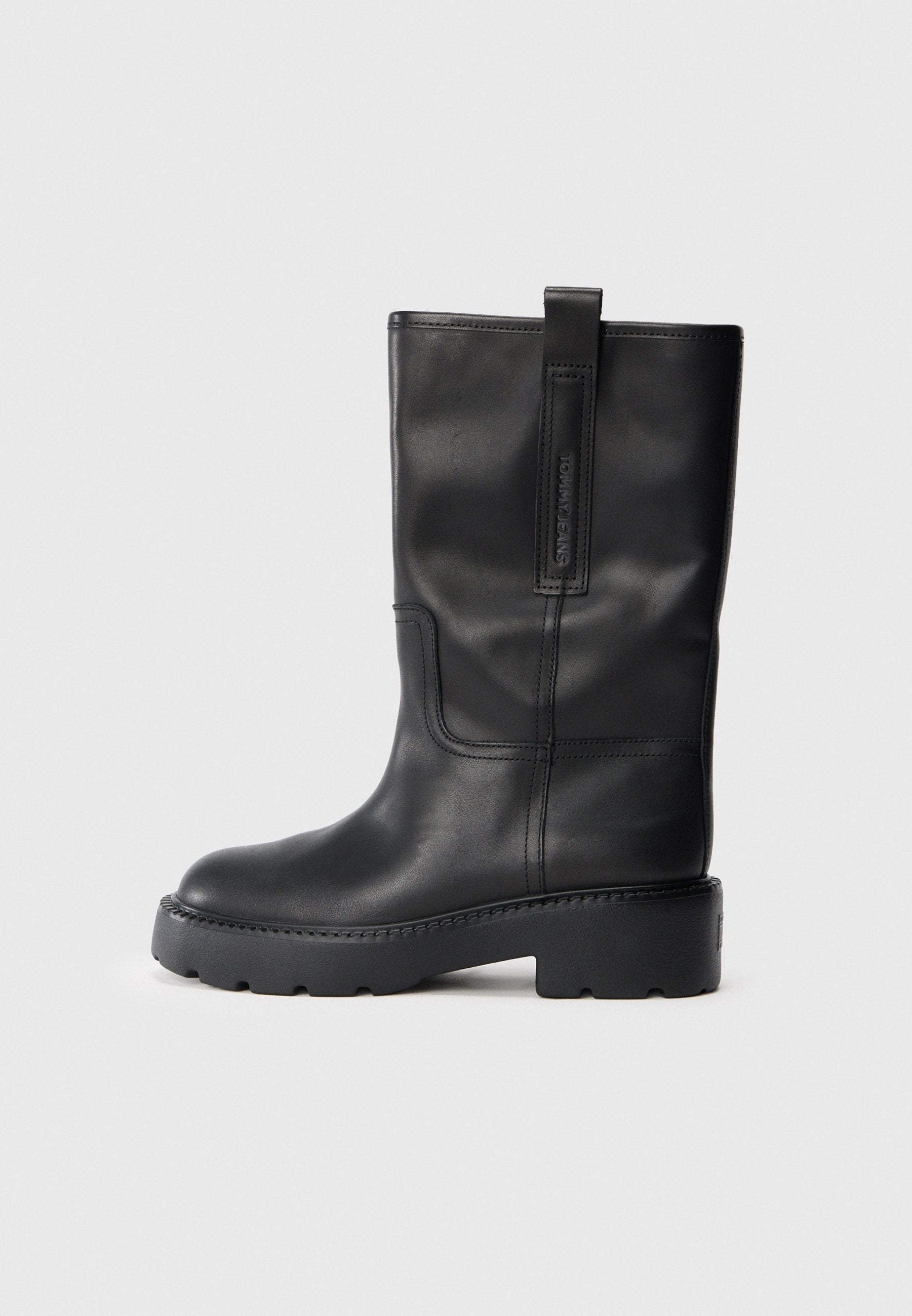 Schwarze Lederstiefel bis zum Knie mit schlankem Design, ausgestattet mit einer dicken Sohle und einem seitlichen Zugschlauf für ein einfaches Anziehen. Auffällige Nähte.