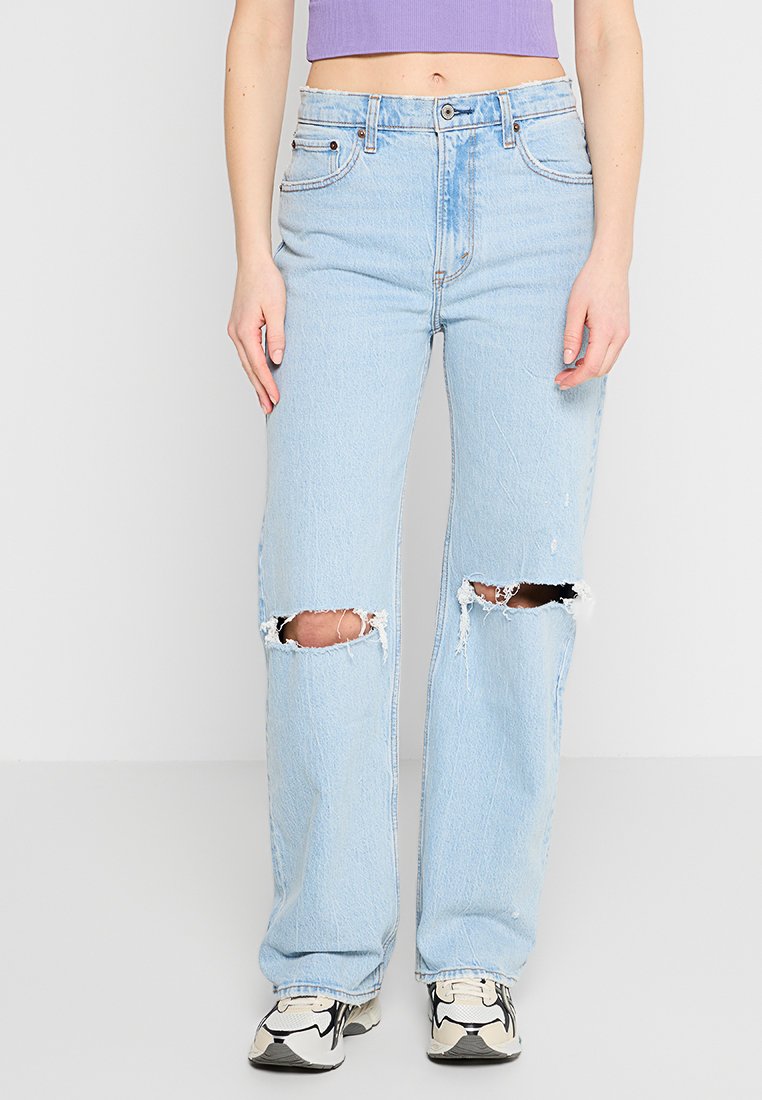 Hellblaue Jeans aus Denim mit lockerer Passform, die an den Knien ausgefranste Risse aufweisen und in einem mittleren Waschgang verarbeitet sind. Klassisches Fünf-Taschen-Design mit Knopfverschluss.