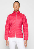 Frau trägt eine leuchtend pinke gesteppte Jacke mit weißen Reißverschlusstaschen und steht vor einem schlichten hellen Hintergrund.