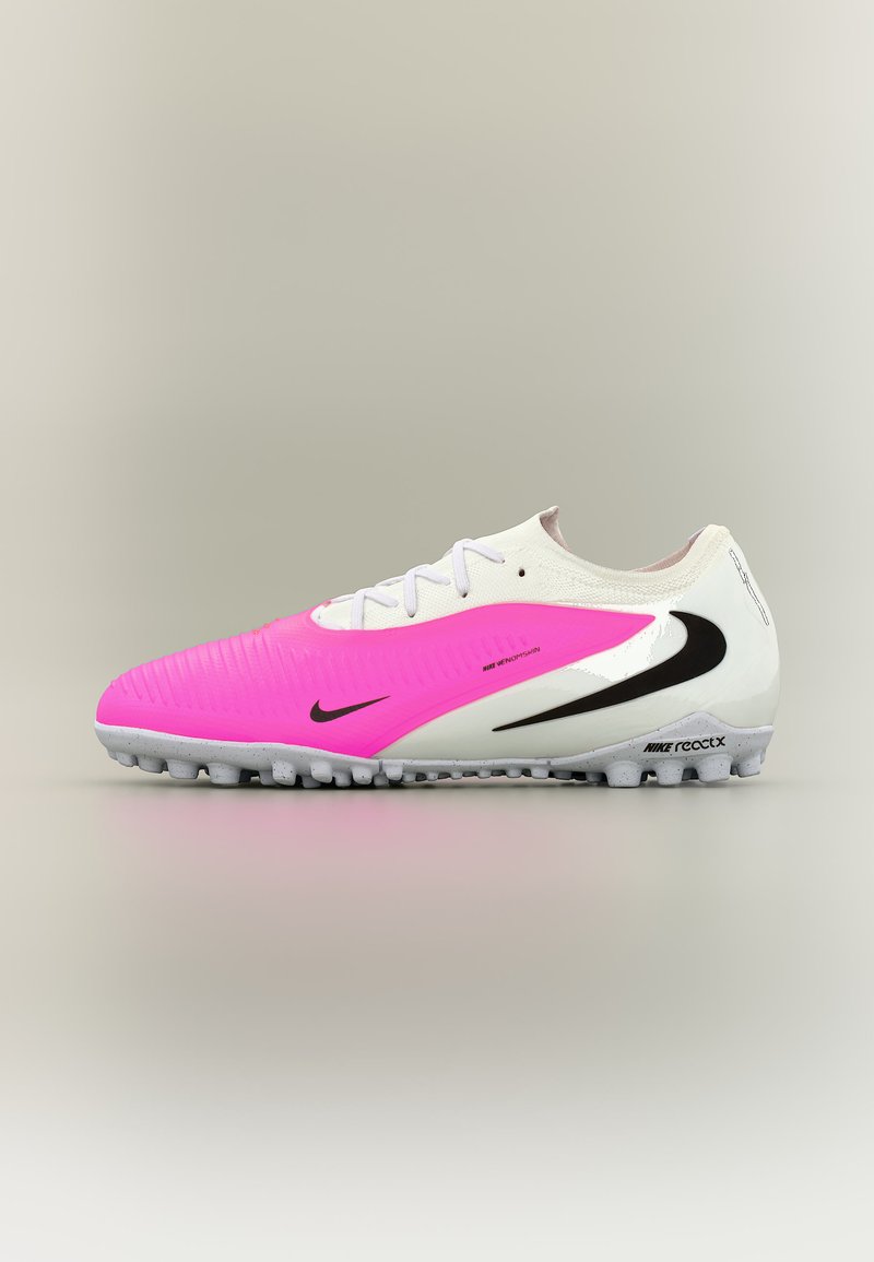 Weißer und rosa Nike React Fußballschuh mit schwarzen Swoosh-Logos und strukturierter Sohle für Kunstrasen, seitlich auf neutralem Hintergrund gezeigt.