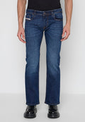 Mann trägt dunkelblaue Jeans mit geradem Bein und schwarze Lederschuhe vor einfachem hellem Hintergrund.