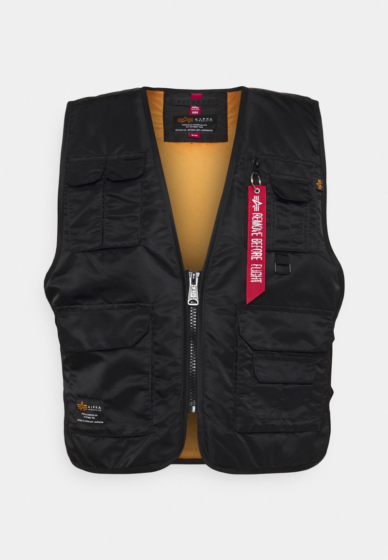 Schwarze Weste mit mehreren Fronttaschen, Reißverschluss und einem leuchtend orangefarbenen Innenfutter. Enthält ein rotes "Remove Before Flight"-Schild.