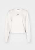 Weißer, kurzes Sweatshirt mit langen Ärmeln und hohem Kragen. Auf der Vorderseite befindet sich ein kleines, burgunderfarbenes "Tommy Jeans"-Logo. Angenehme, glatte Textur.