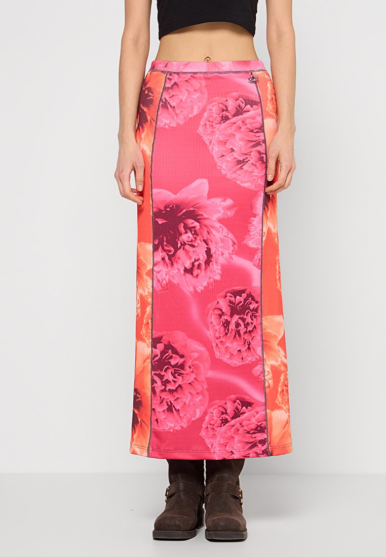 Lange, floral gemusterte Rock in leuchtendem Pink mit glatter Textur, versehen mit schwarzen Seitennaht und Hakenverschluss, kombiniert mit braunen Stiefeletten.
