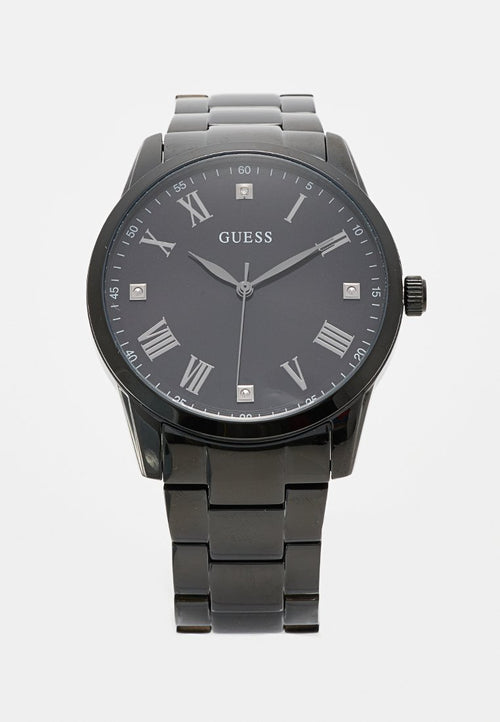Schwarze Guess-Armbanduhr mit Metallarmband, römischen Ziffern, vier Diamant-Markierungen und drei silbernen Zeigern, die 9:10:38 anzeigen.
