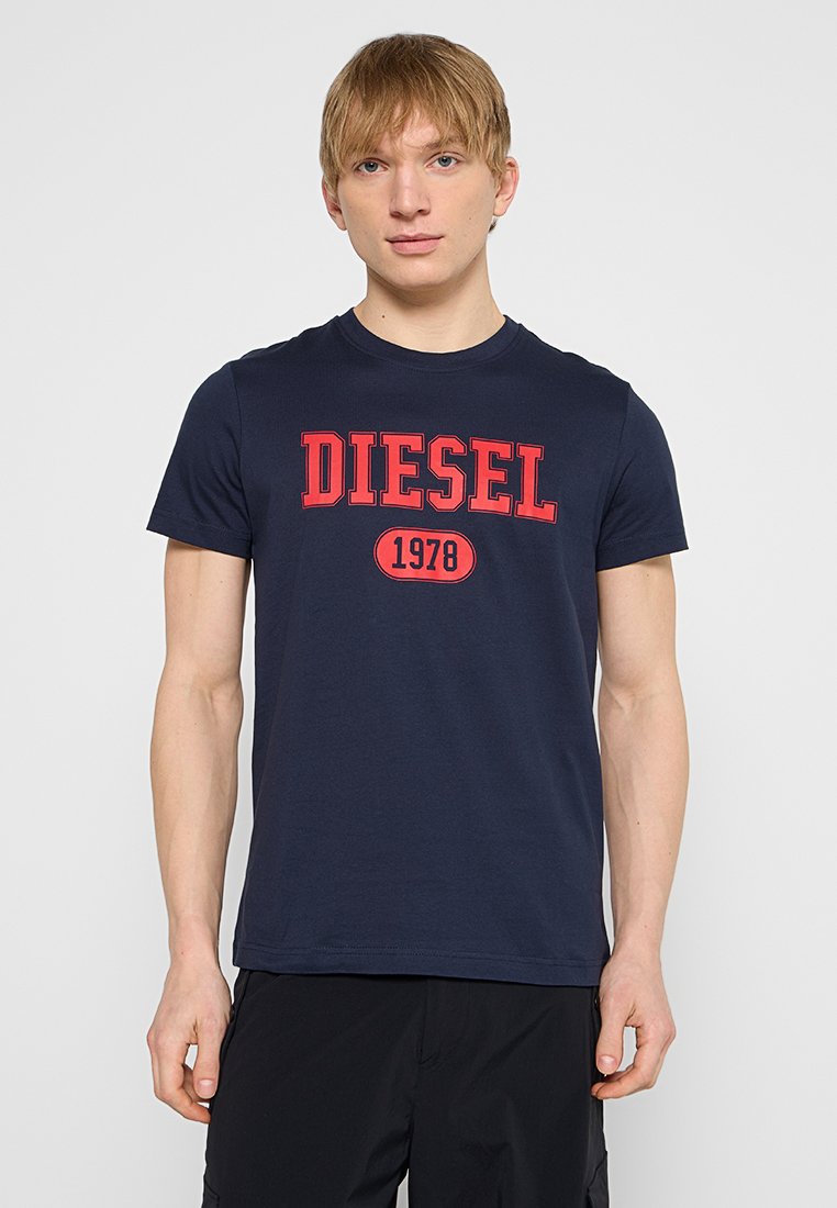 Marineblaues Baumwoll-T-Shirt mit kurzen Ärmeln, das auf der Vorderseite großen roten "DIESEL"-Text und "1978" in einem kreisförmigen Design zeigt.