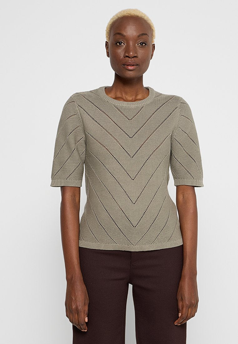 Kurzärmliges Strickoberteil in Olivgrün mit einem Zickzackmuster und Rundhalsausschnitt. Der Stoff hat offene Details, die Textur hinzufügen.