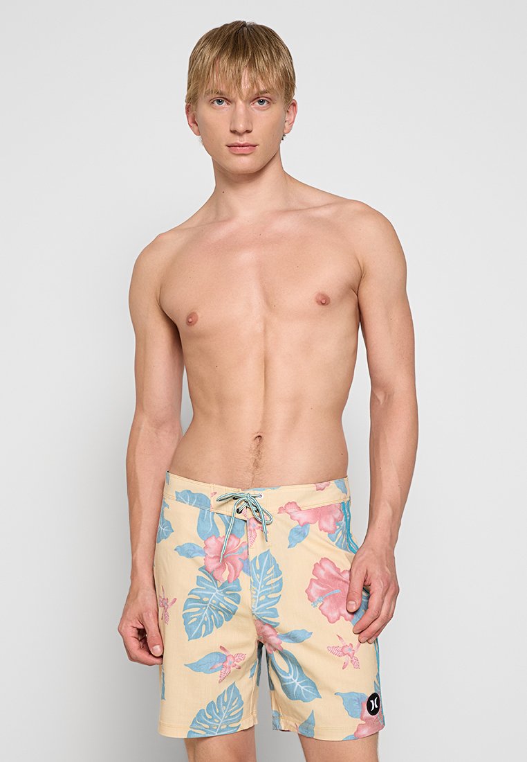 Herren-Badehosen in Hellgelb mit floralem Muster, das blaue Blätter und pinke Blumen zeigt. Aus leichtem Stoff mit elastischem Bund gefertigt.