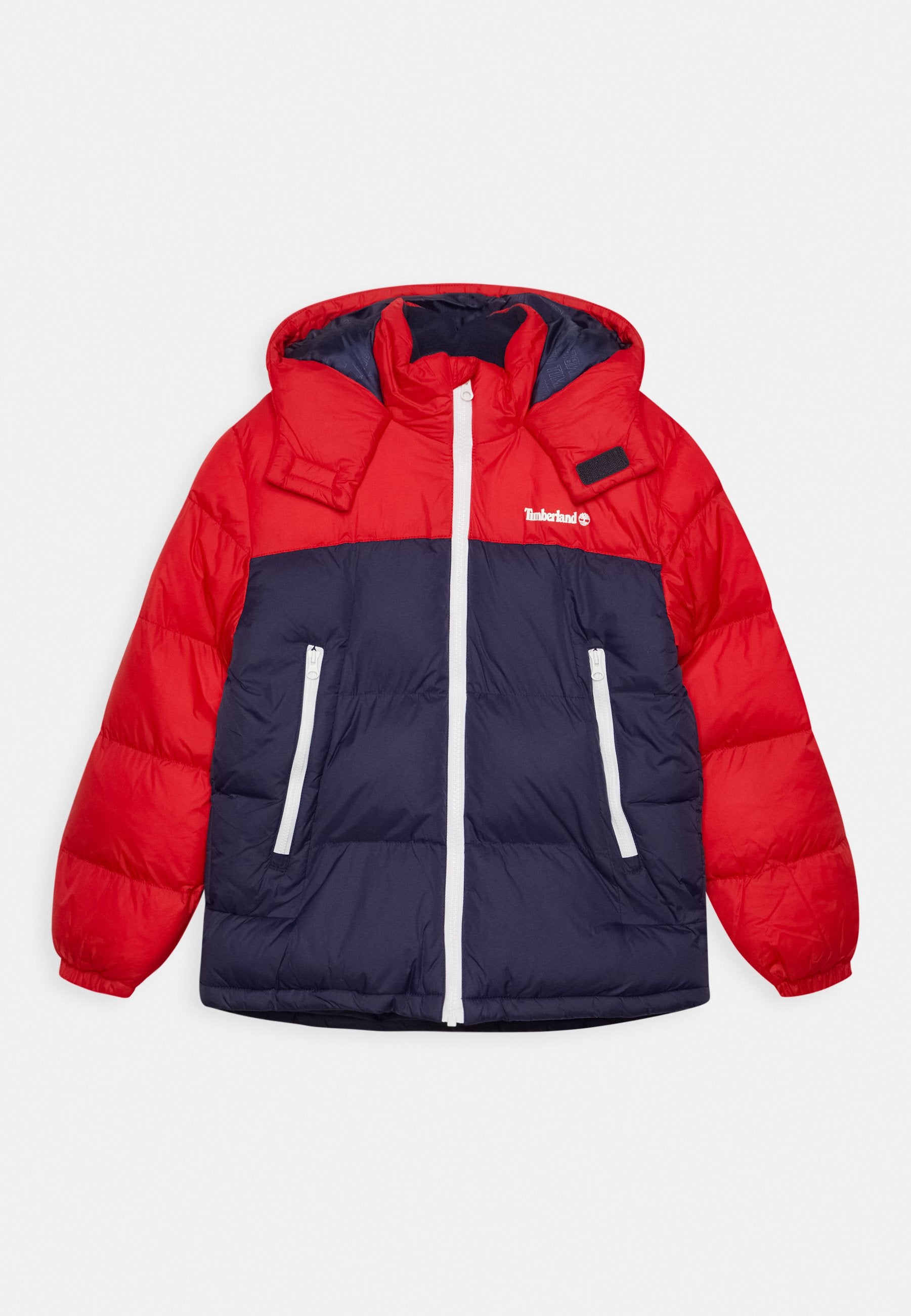 Rote und marineblaue Steppjacke mit Kapuze, ausgestattet mit einem Frontreißverschluss, zwei seitlichen Reißverschlusstaschen und einem Logo auf der Brust.