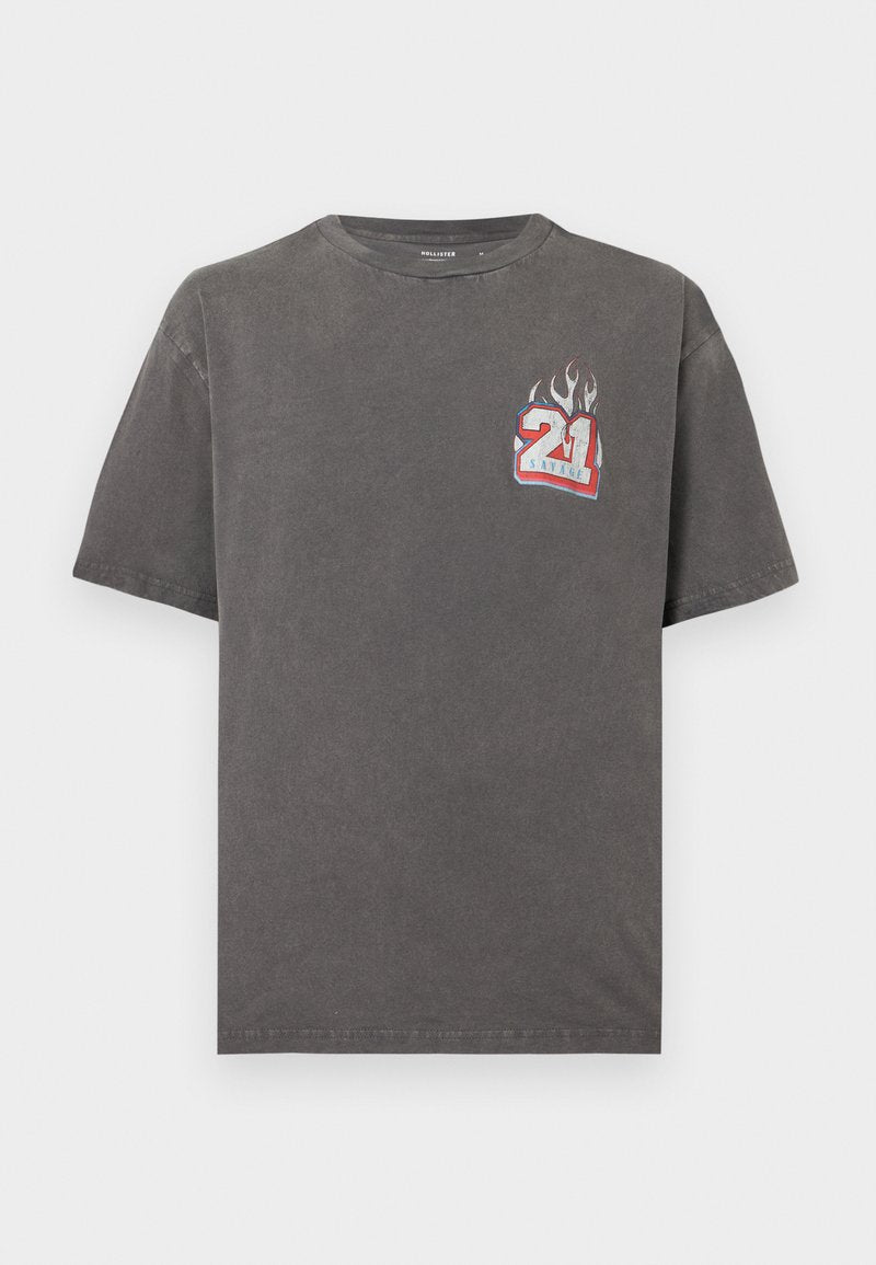 Dunkelgraues kurzärmliges T-Shirt mit einer kleinen Grafik der Zahl "21" in Rot, Weiß und Blau mit Flammen auf der oberen linken Brust.